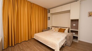 Un dormitorio con cama, armario y cortina.