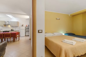 Une chambre avec un lit, un bureau et une kitchenette.