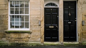 A stone building with a black door labeled '15' and a window with a grid pattern. - Sun St Apartment 5 (Lancaster)