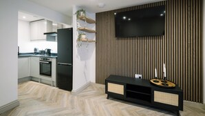 A modern kitchen with white cabinets, a black refrigerator, and a built-in oven. - Sun St Apartment 5 (Lancaster)