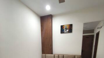Una cama bien hecha con sábanas blancas en una habitación con cabecera de madera y un cuadro en la pared.