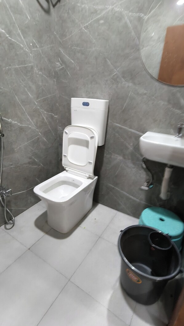 A bathroom with a toilet, a sink, and a mirror. - Shiv Aarambh Home Stay (Ujjain)