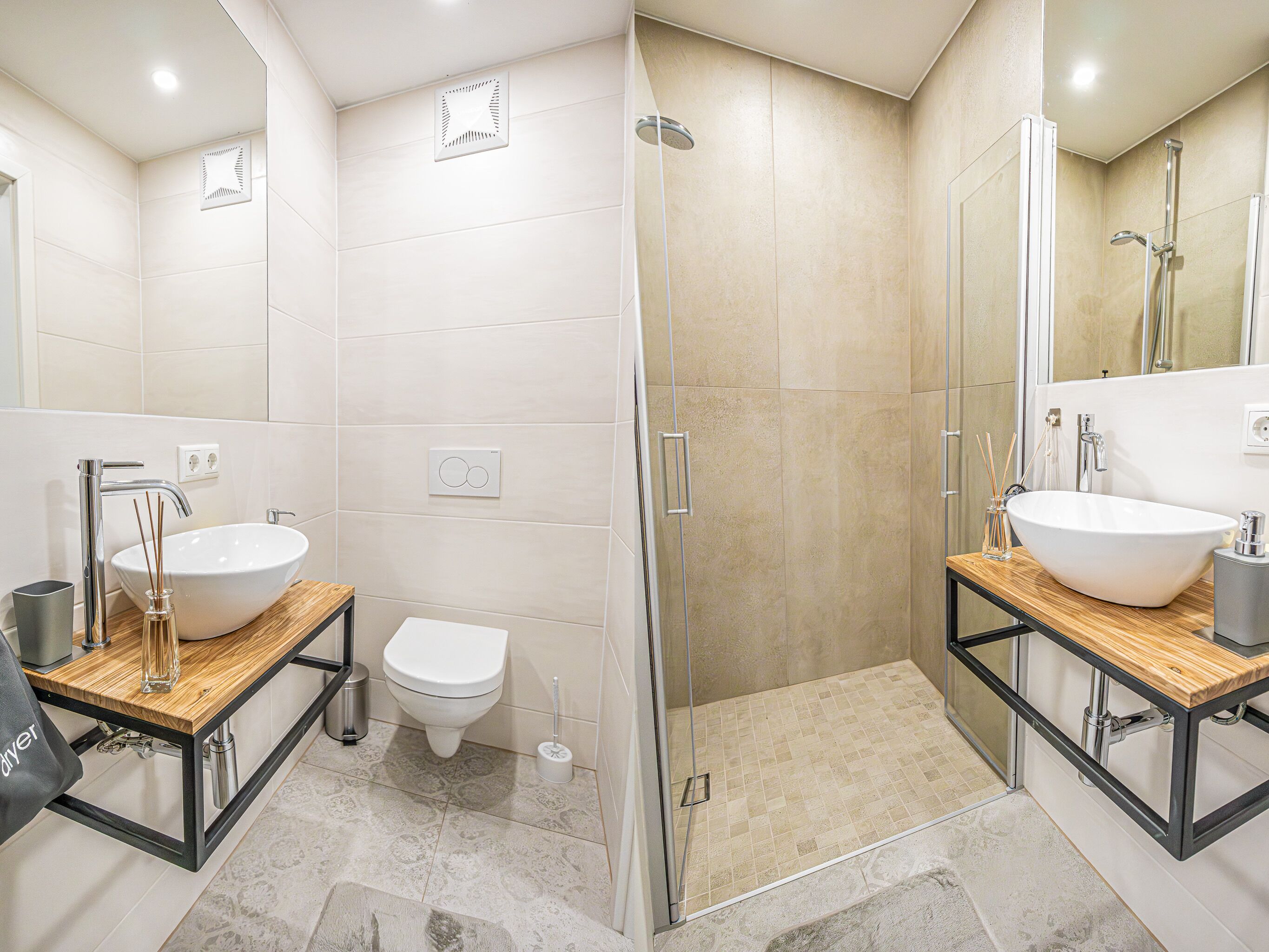 Een moderne badkamer met twee wastafels, een toilet en een douche.