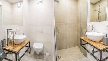 Een moderne badkamer met twee wastafels, een toilet en een douche.