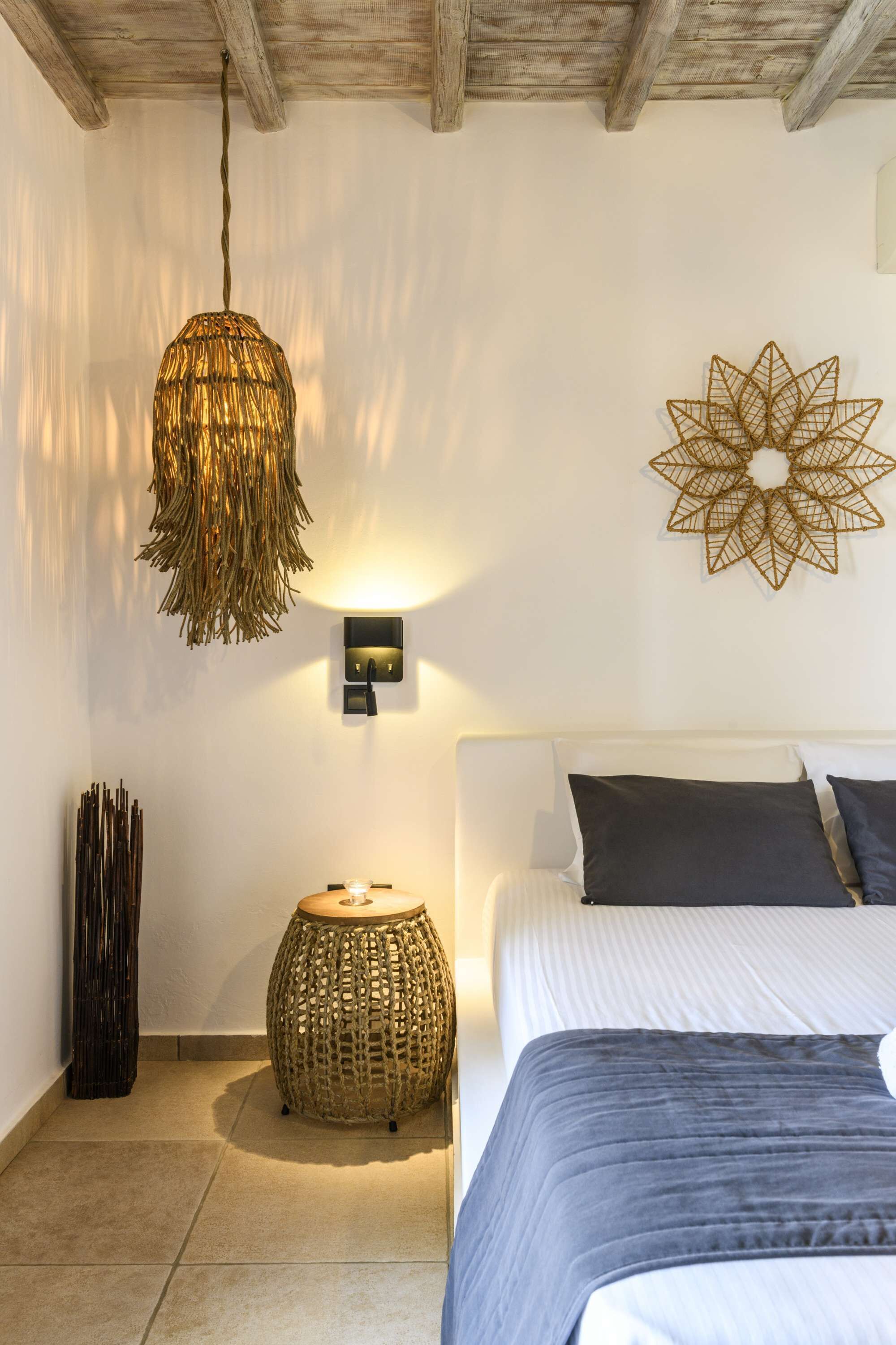 A bedroom with a bed, a hanging light fixture, a wall-mounted light, and a decorative wall piece.