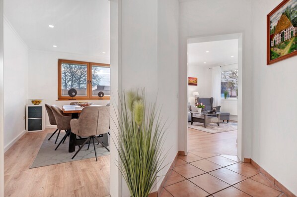 A modern interior with a dining area, a living space, and a view through a doorway. - Apartment “Landhaus Sonnenterrasse” with Private Terrace, Garden, and Wi-Fi (Grasberg)