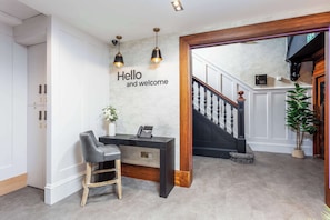 Uma receção com um letreiro que diz 'Hello and welcome', um telefone e uma planta.