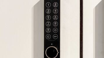 A black elevator control panel with numbered buttons and a circular dial, mounted on a white wall above a brass number '1' door.