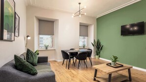A modern living room with a grey sofa, a wooden coffee table, and a dining area with a table and chairs. - The Annick Suite No1 - Donnini Apartments (Irvine)