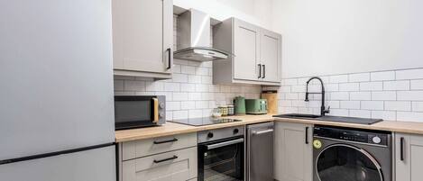 A compact kitchen with a built-in oven, microwave, and dishwasher.