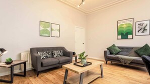 A modern living room with two grey sofas, a wooden coffee table, and a small side table with a lamp. - The Annick Suite No1 - Donnini Apartments (Irvine)