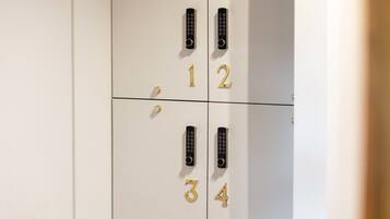 A set of four white lockers with black keypads and gold numbers 1 to 4.