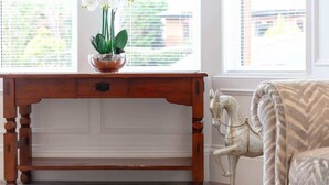Un escritorio de madera con una planta, una escultura decorativa de un caballo y un sillón estampado.
