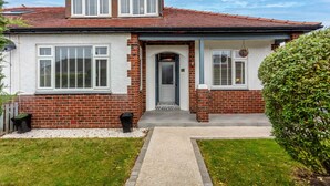 Ein zweistöckiges Haus mit Backsteinfassade, weißem Zierdekor und einem Ziegeldach.