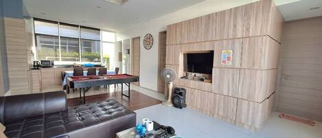 A modern living room with a pool table, leather sofa, and a coffee table with decorative items.