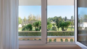 Une fenêtre donnant sur un jardin bien entretenu et des arbres.