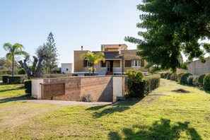 Ein modernes, zweistöckiges Haus mit flachem Dach, Hauseingang und kleinem Balkon.