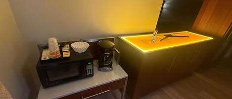 A compact kitchenette with a microwave, coffee maker, and a small countertop.