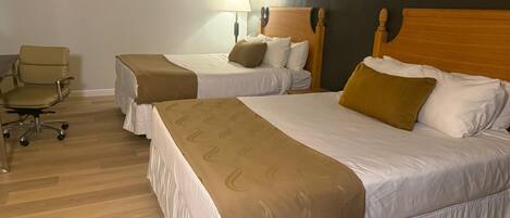 A hotel room with two beds, a desk, and a chair.