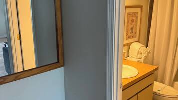 Un baño con un espejo de marco de madera, un lavabo, un inodoro y una cortina de ducha.