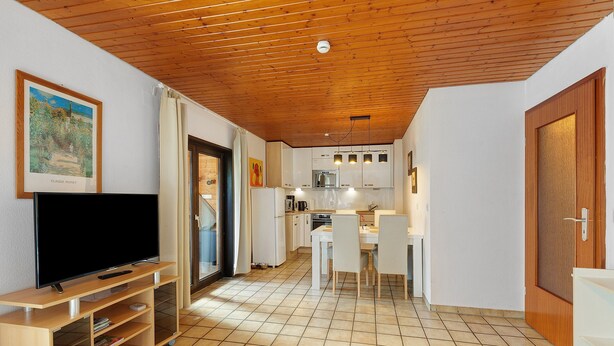 A compact living space with a kitchen, dining area, and entertainment unit. - Apartment 'Heve' with Shared Terrace, Private Garden and Wi-Fi (Möhnesee)