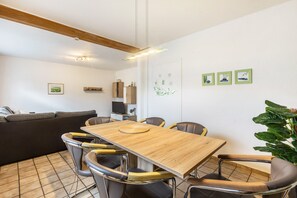 Un comedor moderno con una mesa y sillas de madera, un sofá, un televisor y una planta.