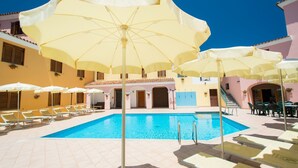 A pool area with multiple sun umbrellas and lounge chairs. - Apartment Surrounded by Nature (Orosei)