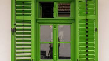 Una ventana con contraventanas verdes y un cartel arriba.