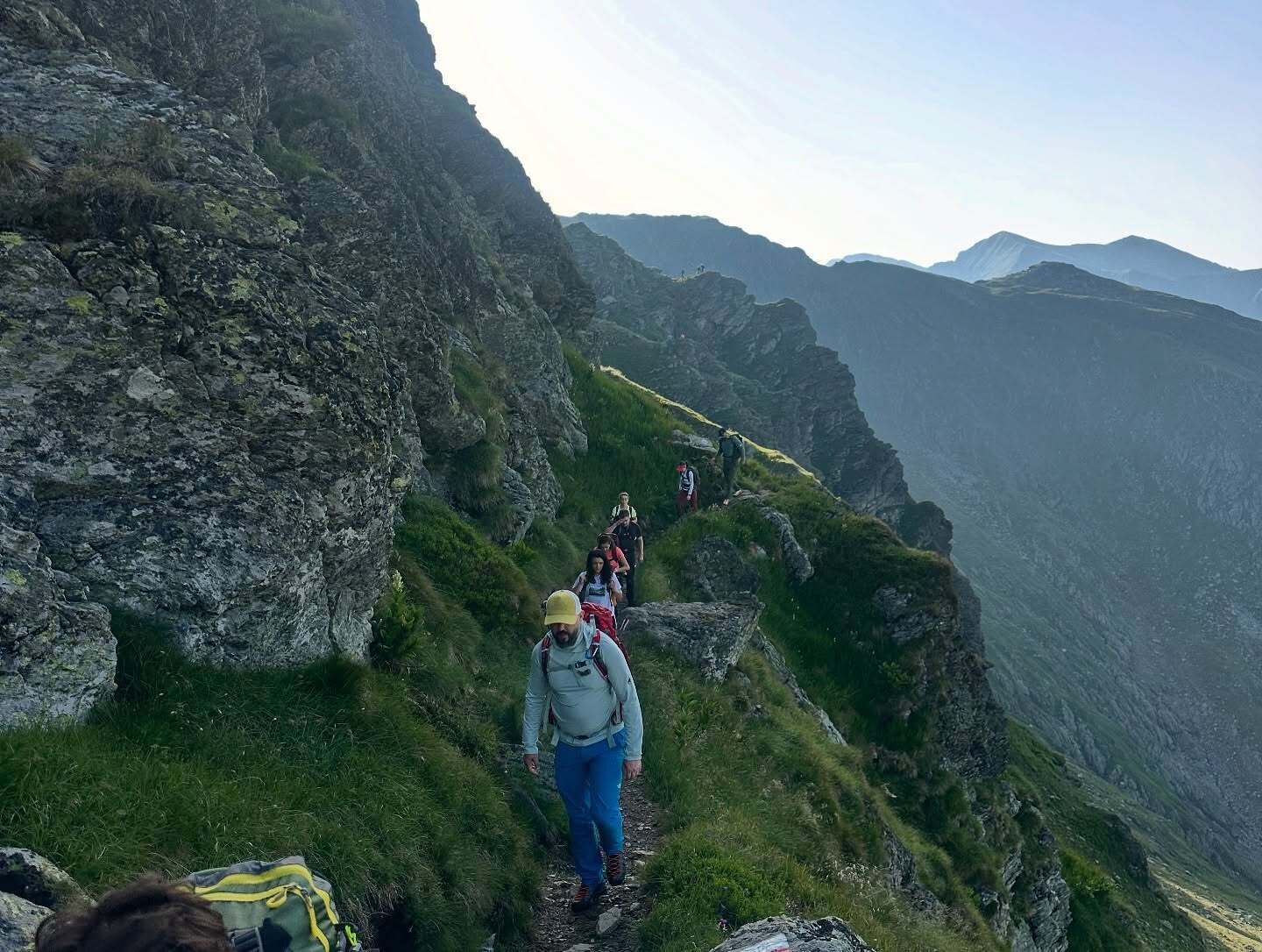Un sendero de montaña estrecho con excursionistas.
