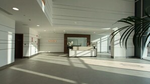 A spacious lobby with a reception desk, a large potted plant, and a sign that reads "SAMIA". - Modern Studio in Azizi Samia by Bespoke (Dubai)