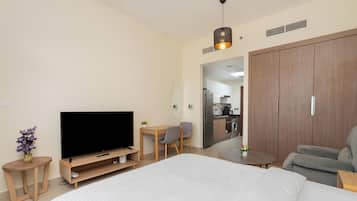 Habitación de hotel con una cama grande, un televisor, una mesita, una silla y un armario.
