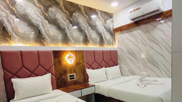 Une chambre d’hôtel avec deux lits, des éléments décoratifs en marbre sur les murs, un mur d’accent en bois et un appareil de climatisation.