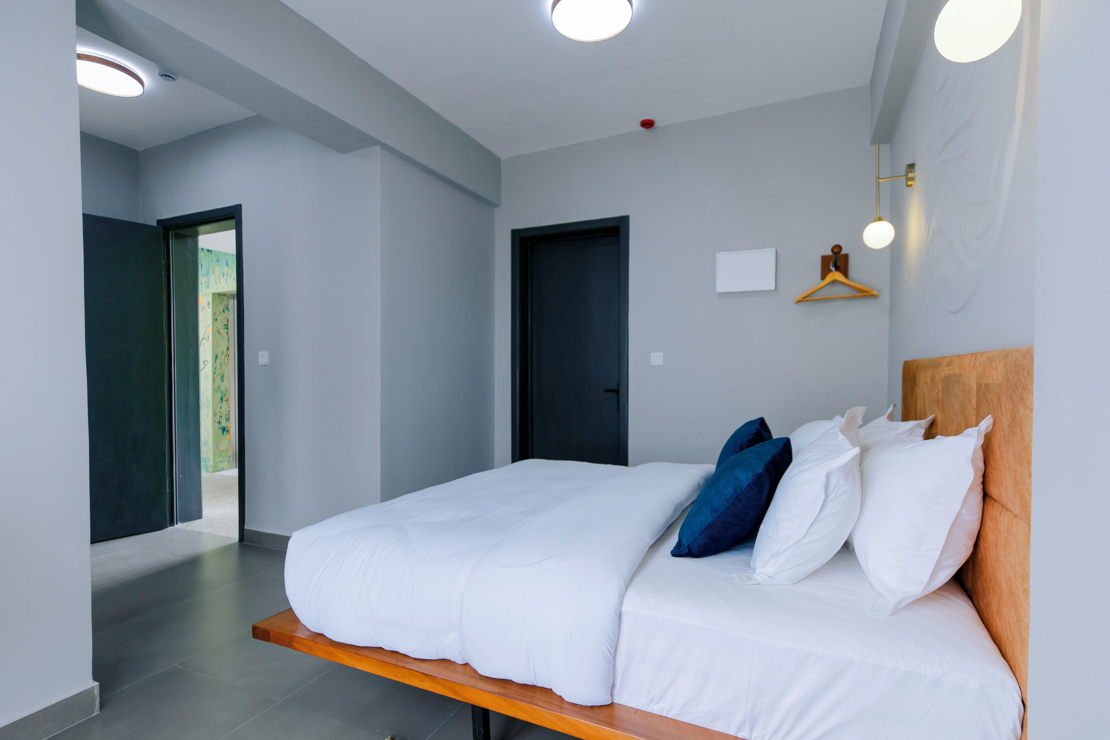 A modern hotel room with a large bed, a wooden headboard, and a view of a balcony.