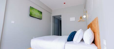 A modern hotel room with a bed, a television, and a small table with a remote control.