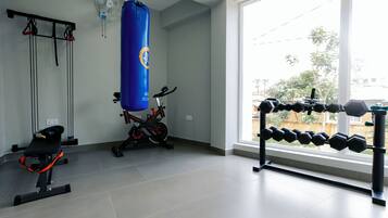 A gym with a punching bag, exercise bike, and dumbbells.