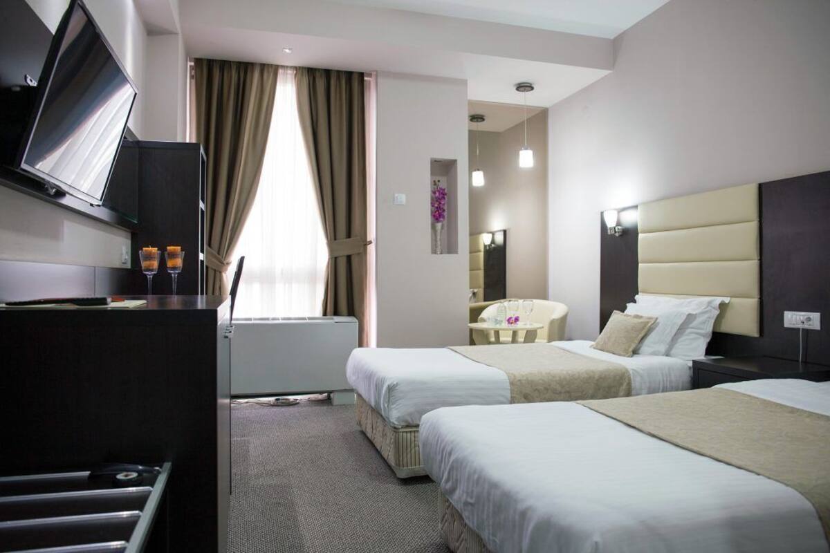 Une chambre d’hôtel avec deux lits, un bureau avec une télévision, une petite table et un miroir.