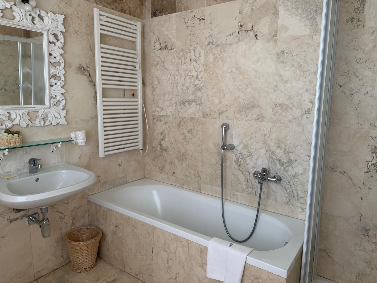 Un baño con bañera blanca, lavamanos, espejo y ducha.