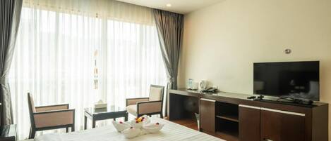 A hotel room with a bed, a desk, a TV, and a window with curtains.