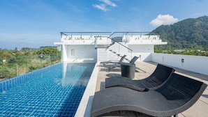 A rooftop swimming pool with lounge chairs, a staircase, and a view of a lush mountain. - Yenna Apartment (Kamala)