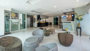 A modern hotel lobby with wicker furniture, a reception desk, and a glass door entrance. - Yenna Apartment (Kamala)