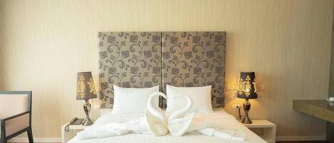 Una habitación de hotel con una cama grande, dos lámparas de noche, una mesita de noche y una silla.