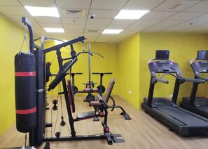 Une salle de sport équipée de matériel d’exercice, notamment un sac de frappe, un banc de développé couché et des tapis de course.