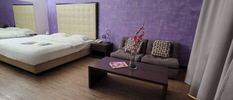 Una habitación de hotel con una cama, un sofá, una mesa de centro y una mesita de noche.