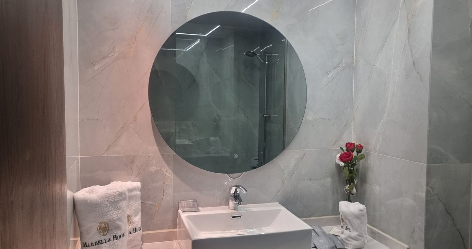 Un baño con un espejo grande, un lavabo y un perchero para toallas.