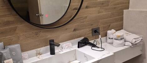 A modern bathroom with a marble vanity, a round mirror, and a towel rack with branded towels.