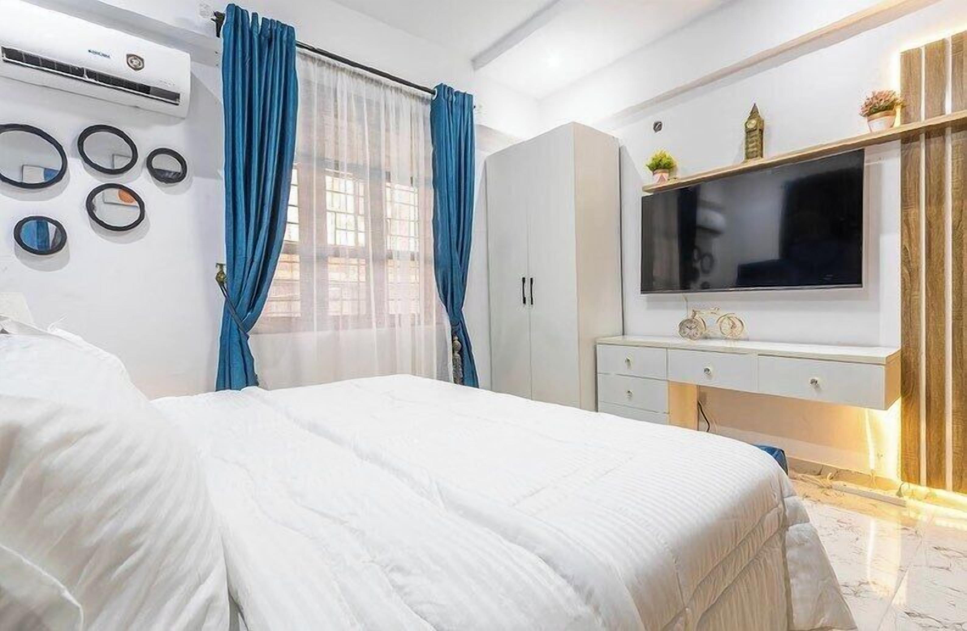Un dormitorio con cama, televisor montado en la pared, armario y aire acondicionado.