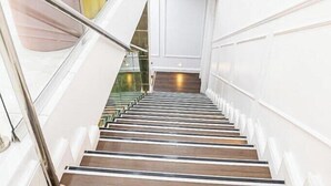 A staircase with wooden steps and white walls, leading to a room with a large window. - Favour Shortlet Apartment (Lagos)