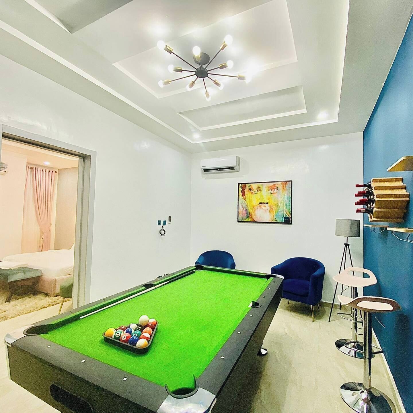 Una habitación moderna con una mesa de billar, un aplique de techo y un cuadro en la pared.