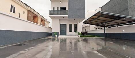 A modern building with a flat roof, a central entrance, and a covered outdoor area.