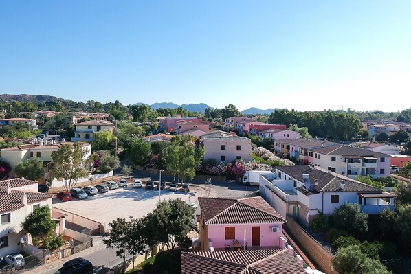 A residential area with houses, a parking lot, and a clear sky. - Comfy Flat With Terrace and Pool (Orosei)